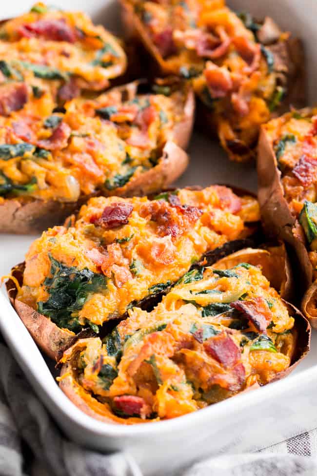These twice baked sweet potatoes can be served as a healthy meal or side dish - your choice!  They're packed with a savory mixture of caramelized onions, spinach and bacon and baked to perfection.  They're family approved, Paleo, Whole30 compliant, and dairy-free.  