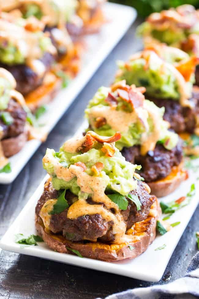 These sweet potato sliders are loaded with goodies!  Taco seasoned burger patties over roasted sweet potato "buns" topped with an easy guacamole, chipotle ranch and crumbled bacon.  Perfect as an appetizer, party food or a fun meal!  Paleo and Whole30 compliant, family approved!