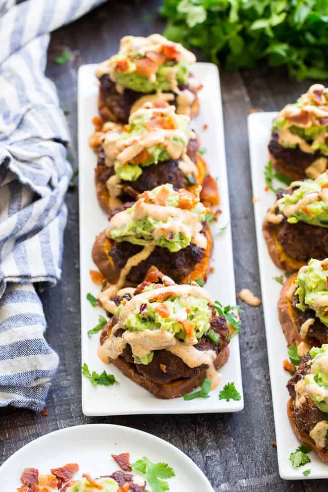 These sweet potato sliders are loaded with goodies!  Taco seasoned burger patties over roasted sweet potato "buns" topped with an easy guacamole, chipotle ranch and crumbled bacon.  Perfect as an appetizer, party food or a fun meal!  Paleo and Whole30 compliant, family approved!