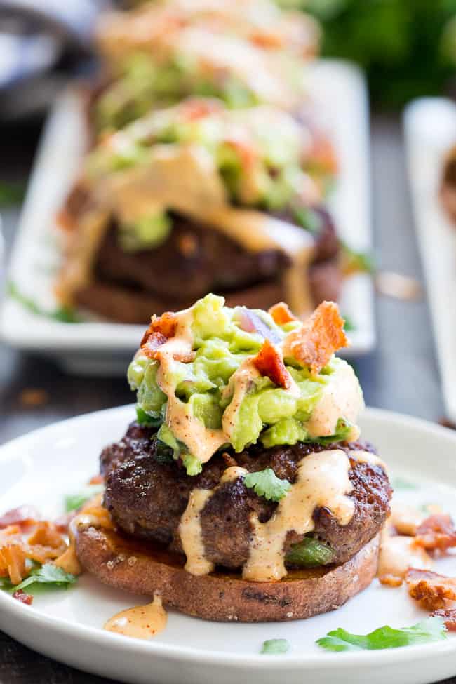 These sweet potato sliders are loaded with goodies!  Taco seasoned burger patties over roasted sweet potato "buns" topped with an easy guacamole, chipotle ranch and crumbled bacon.  Perfect as an appetizer, party food or a fun meal!  Paleo and Whole30 compliant, family approved!