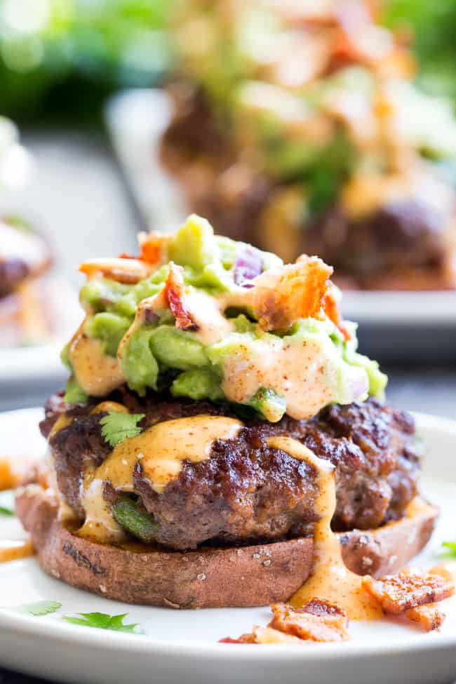 These sweet potato sliders are loaded with goodies!  Taco seasoned burger patties over roasted sweet potato "buns" topped with an easy guacamole, chipotle ranch and crumbled bacon.  Perfect as an appetizer, party food or a fun meal!  Paleo and Whole30 compliant, family approved!