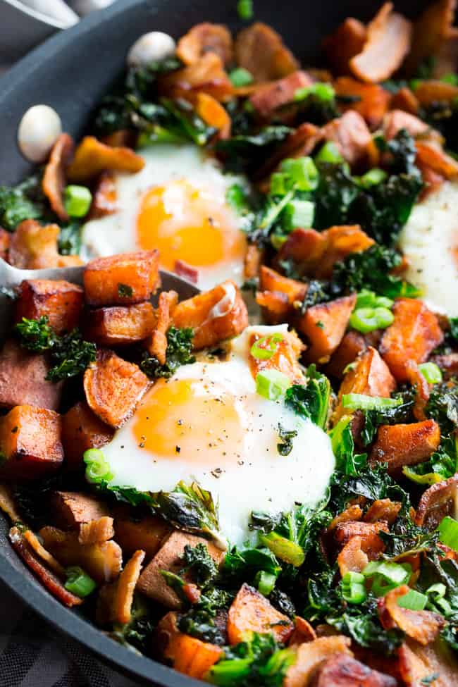 This simple sweet potato hash with kale and bacon is your new paleo and Whole30 go-to breakfast!  Crispy bacon, kale, and sweet potatoes are seasoned and cooked up perfectly in a big skillet, then topped with eggs and garnished with green onion.  It doesn't get easier or more delicious than this hash!  