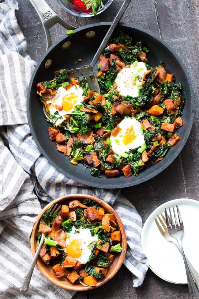 This simple sweet potato hash with kale and bacon is your new paleo and Whole30 go-to breakfast!  Crispy bacon, kale, and sweet potatoes are seasoned and cooked up perfectly in a big skillet, then topped with eggs and garnished with green onion.  It doesn't get easier or more delicious than this hash!  
