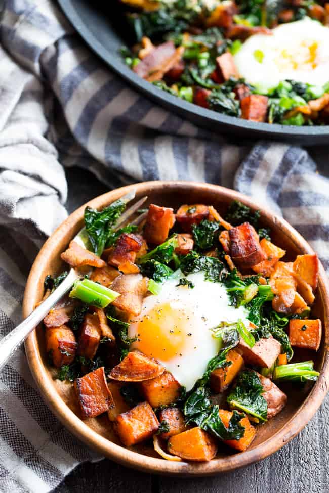 This simple sweet potato hash with kale and bacon is your new paleo and Whole30 go-to breakfast!  Crispy bacon, kale, and sweet potatoes are seasoned and cooked up perfectly in a big skillet, then topped with eggs and garnished with green onion.  It doesn't get easier or more delicious than this hash!  