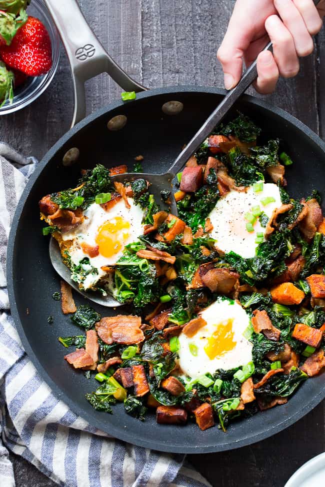 This simple sweet potato hash with kale and bacon is your new paleo and Whole30 go-to breakfast!  Crispy bacon, kale, and sweet potatoes are seasoned and cooked up perfectly in a big skillet, then topped with eggs and garnished with green onion.  It doesn't get easier or more delicious than this hash!  