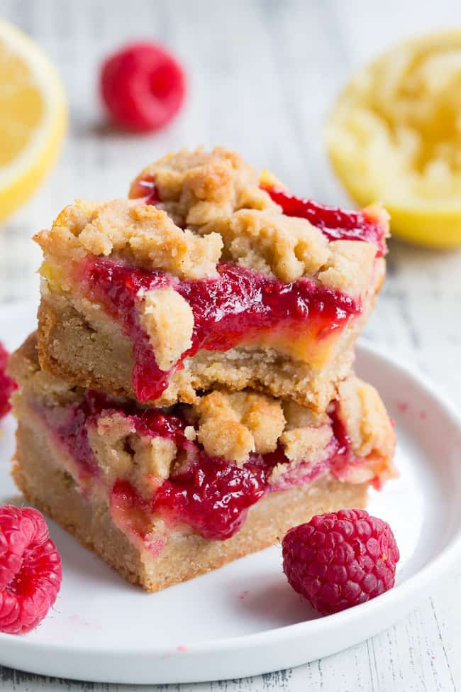 These paleo raspberry lemon bars are absolutely heaven!   A lemon cookie crust is topped with creamy tart sweet lemon curd, homemade raspberry sauce and more cookie crumbles to top.  Everything is baked to perfection and cut into bars for the ultimate dessert!  Gluten-free, dairy-free, no refined sugar, grain free.