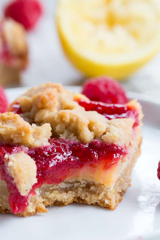 These paleo raspberry lemon bars are absolutely heaven!   A lemon cookie crust is topped with creamy tart sweet lemon curd, homemade raspberry sauce and more cookie crumbles to top.  Everything is baked to perfection and cut into bars for the ultimate dessert!  Gluten-free, dairy-free, no refined sugar, grain free.