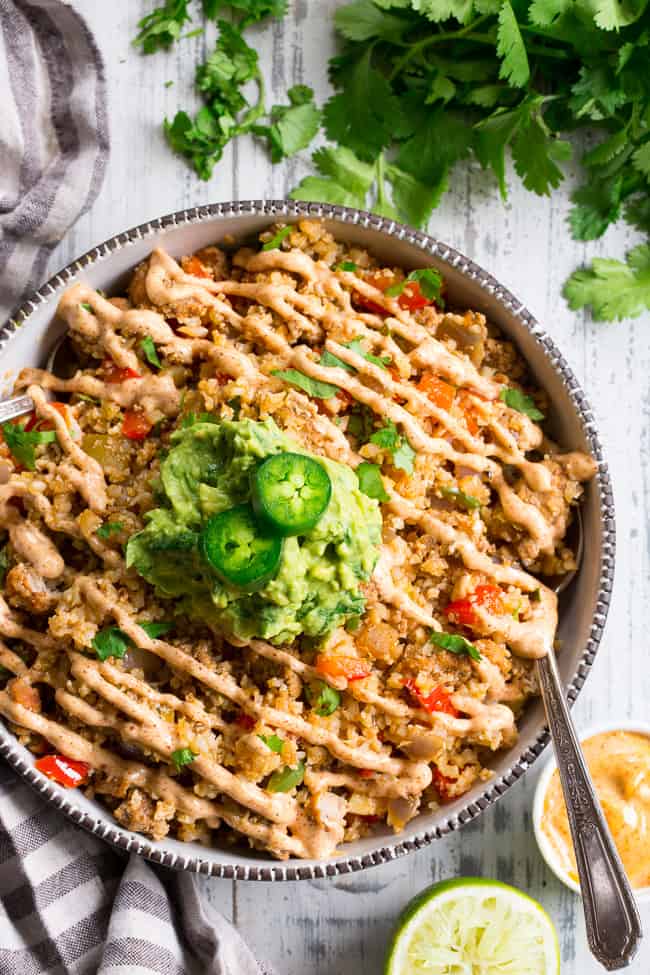 This Mexican Cauliflower Rice is packed with veggies, protein, and lots of flavor and spice!  It's topped with an easy guacamole and chipotle ranch sauce for a tasty, filling meal that's Paleo, Whole30 compliant and keto friendly.