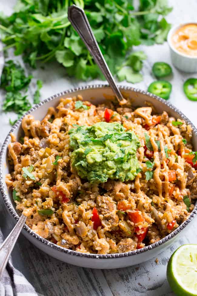 This Mexican Cauliflower Rice is packed with veggies, protein, and lots of flavor and spice!  It's topped with an easy guacamole and chipotle ranch sauce for a tasty, filling meal that's Paleo, Whole30 compliant and keto friendly.