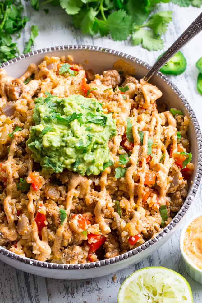 This Mexican Cauliflower Rice is packed with veggies, protein, and lots of flavor and spice!  It's topped with an easy guacamole and chipotle ranch sauce for a tasty, filling meal that's Paleo, Whole30 compliant and keto friendly.