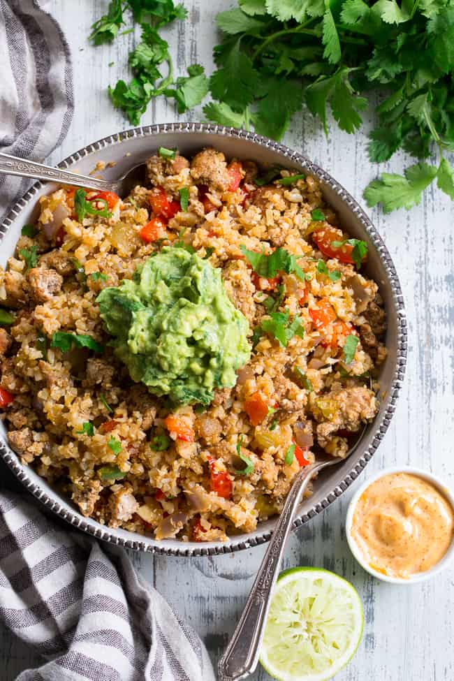 This Mexican Cauliflower Rice is packed with veggies, protein, and lots of flavor and spice!  It's topped with an easy guacamole and chipotle ranch sauce for a tasty, filling meal that's Paleo, Whole30 compliant and keto friendly.