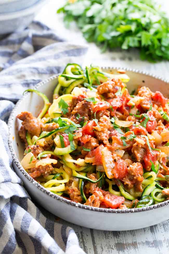 These zucchini noodles are made deliciously savory with lots of spicy Italian sausage, and a creamy tomato sauce.  Quick to throw together on a weeknight and easy to make ahead of time too!  It's a filling, family friendly lunch or dinner that's Paleo, Whole30, dairy free and low carb too!