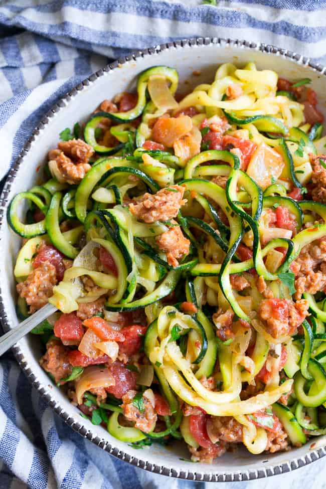 These zucchini noodles are made deliciously savory with lots of spicy Italian sausage, and a creamy tomato sauce.  Quick to throw together on a weeknight and easy to make ahead of time too!  It's a filling, family friendly lunch or dinner that's Paleo, Whole30, dairy free and low carb too!
