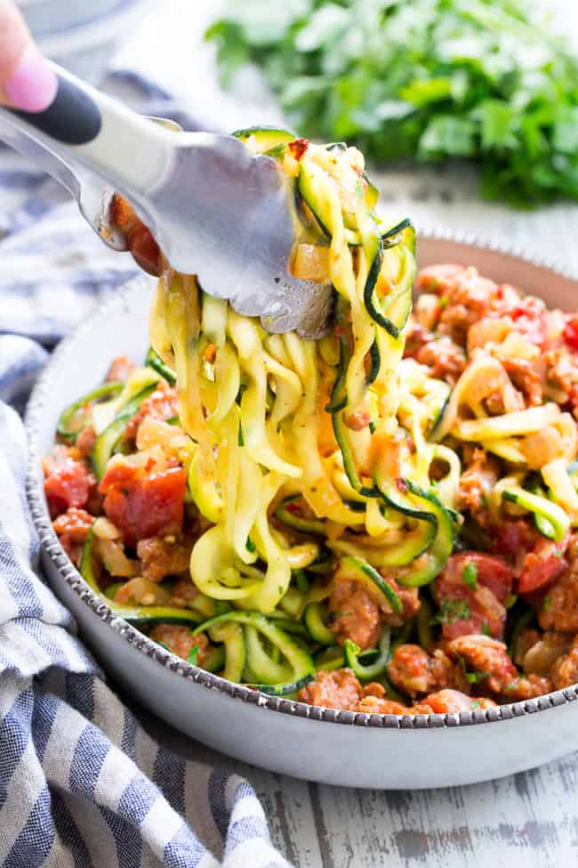 These zucchini noodles are made deliciously savory with lots of spicy Italian sausage, and a creamy tomato sauce.  Quick to throw together on a weeknight and easy to make ahead of time too!  It's a filling, family friendly lunch or dinner that's Paleo, Whole30, dairy free and low carb too!