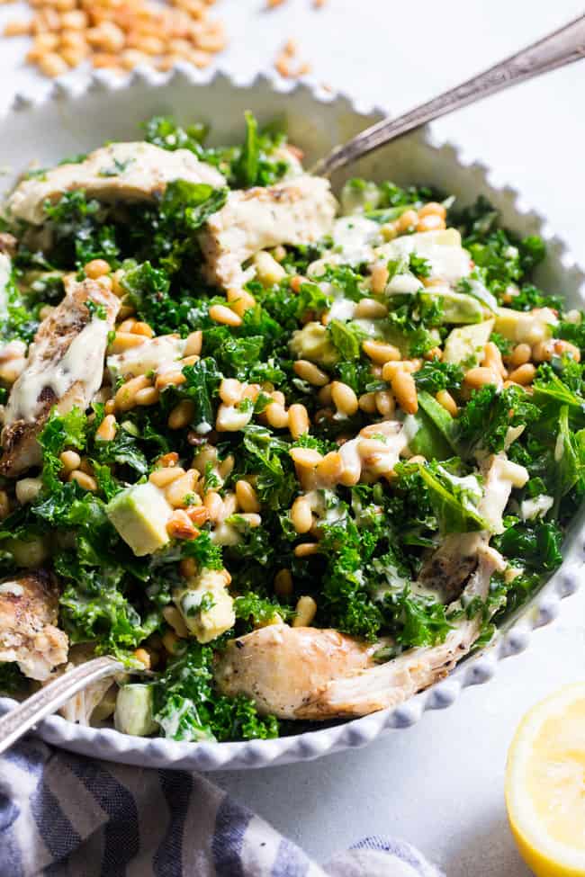 This Paleo and Whole30 Kale Chicken Caesar Salad is an easy, healthy lunch or dinner packed with so much flavor!  Grilled chicken is tossed with avocado, toasted pine nuts, chopped kale, and a creamy homemade dairy-free caesar dressing for a deliciously savory salad that you'll want to make again and again.