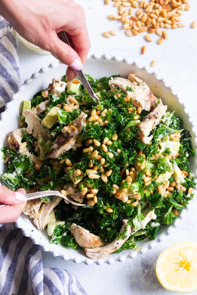 This Paleo and Whole30 Kale Chicken Caesar Salad is an easy, healthy lunch or dinner packed with so much flavor!  Grilled chicken is tossed with avocado, toasted pine nuts, chopped kale, and a creamy homemade dairy-free caesar dressing for a deliciously savory salad that you'll want to make again and again.