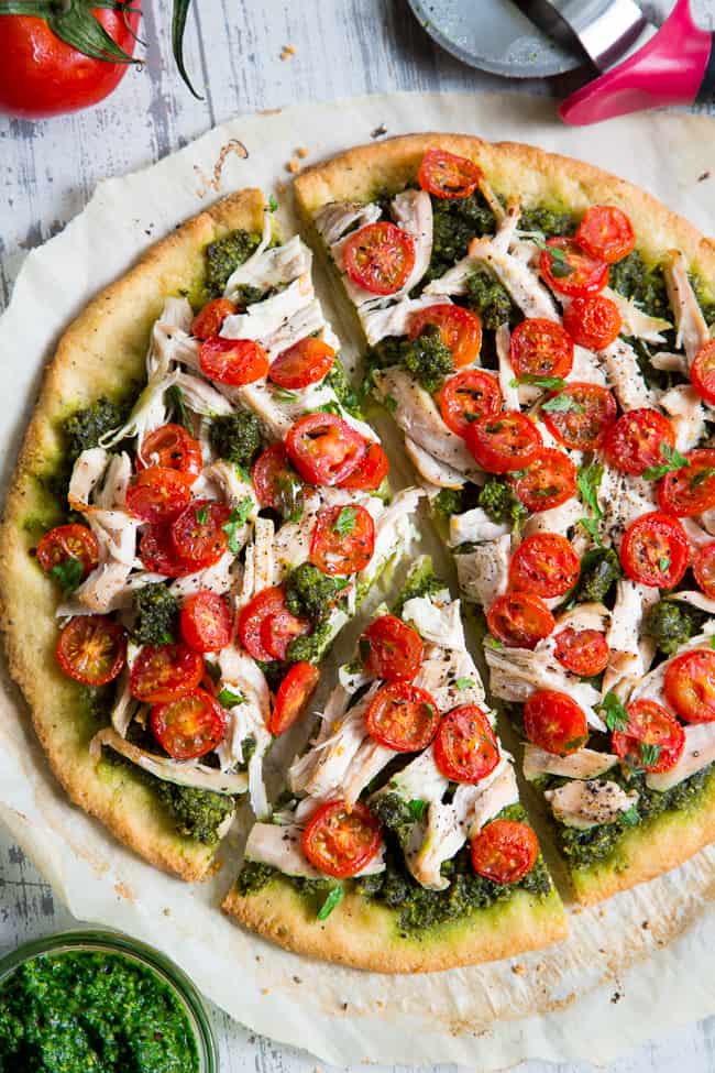 This simple chicken pesto pizza starts with the perfect quick and easy paleo pizza crust, topped with a flavor-packed dairy-free homemade pesto, shredded chicken and cherry tomatoes.  This fun meal great for dinner or lunch, is kid approved, grain-free, dairy-free and insanely delicious.