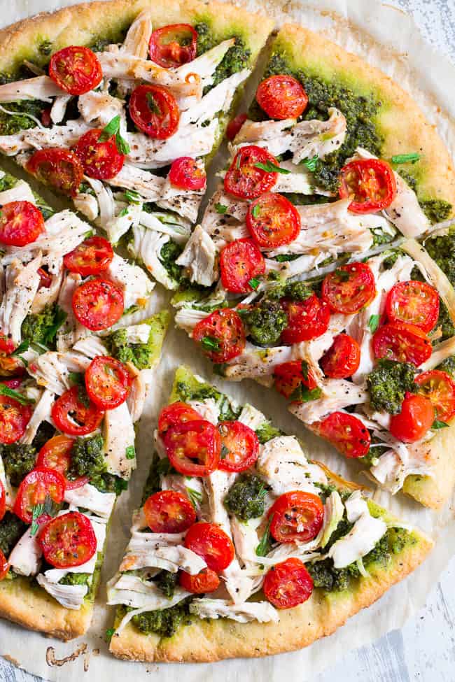 This simple chicken pesto pizza starts with the perfect quick and easy paleo pizza crust, topped with a flavor-packed dairy-free homemade pesto, shredded chicken and cherry tomatoes.  This fun meal great for dinner or lunch, is kid approved, grain-free, dairy-free and insanely delicious.