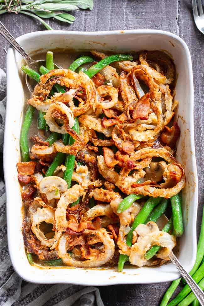 green bean casserole with crispy bacon and fried onions on top in a casserole dish