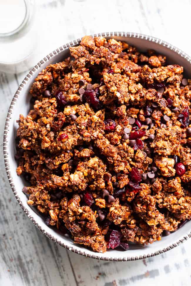 This Paleo gingerbread granola is perfect for snacking or breakfast! The crunchy granola clusters are sweetened with maple and molasses, baked until toasty, and mixed with sweet cranberries and dark chocolate chips.  Vegan, grain free, dairy free.