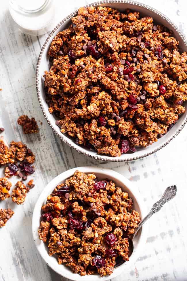 This Paleo gingerbread granola is perfect for snacking or breakfast! The crunchy granola clusters are sweetened with maple and molasses, baked until toasty, and mixed with sweet cranberries and dark chocolate chips.  Vegan, grain free, dairy free.