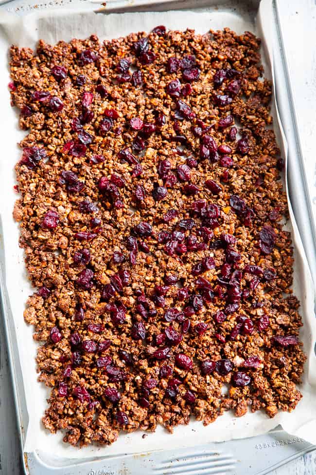 This Paleo gingerbread granola is perfect for snacking or breakfast! The crunchy granola clusters are sweetened with maple and molasses, baked until toasty, and mixed with sweet cranberries and dark chocolate chips.  Vegan, grain free, dairy free.