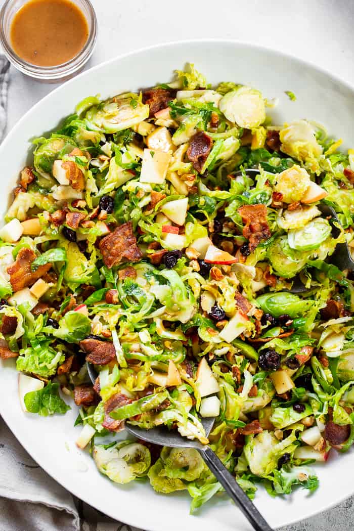 This shredded Brussels sprouts salad is loaded with so many delicious things!  Sweet chopped apples, crispy bacon, toasted hazelnuts and a sweet tangy apple vinaigrette.  It’s paleo, dairy-free, with a Whole30 option and perfect for a crowd or as a make ahead lunch.