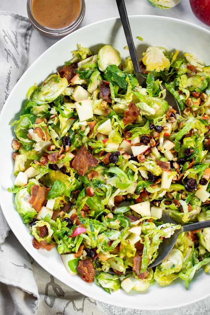 This shredded Brussels sprouts salad is loaded with so many delicious things!  Sweet chopped apples, crispy bacon, toasted hazelnuts and a sweet tangy apple vinaigrette.  It’s paleo, dairy-free, with a Whole30 option and perfect for a crowd or as a make ahead lunch.