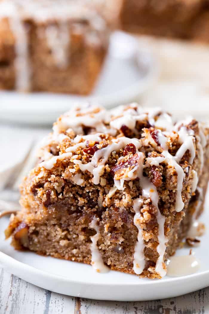 a square slice of coffee cake with a pecan streusel crumb topping and white frosting drizzle