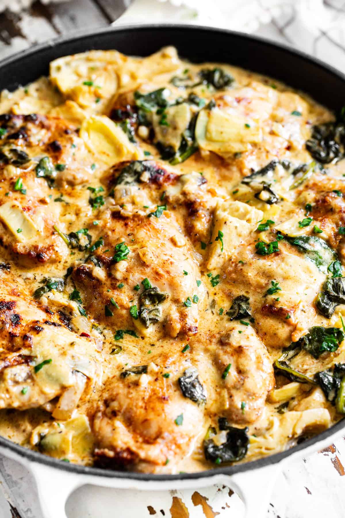 Creamy spinach artichoke chicken in a skillet with chicken thighs, spinach, artichoke hearts and rich dairy-free cream sauce.