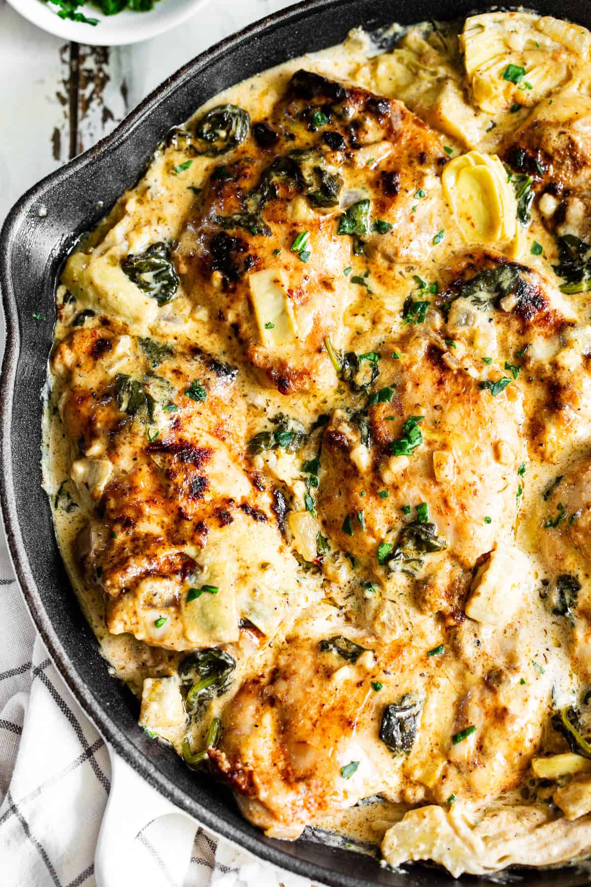 Golden chicken thighs coated in creamy spinach artichoke sauce with garlic and herbs.