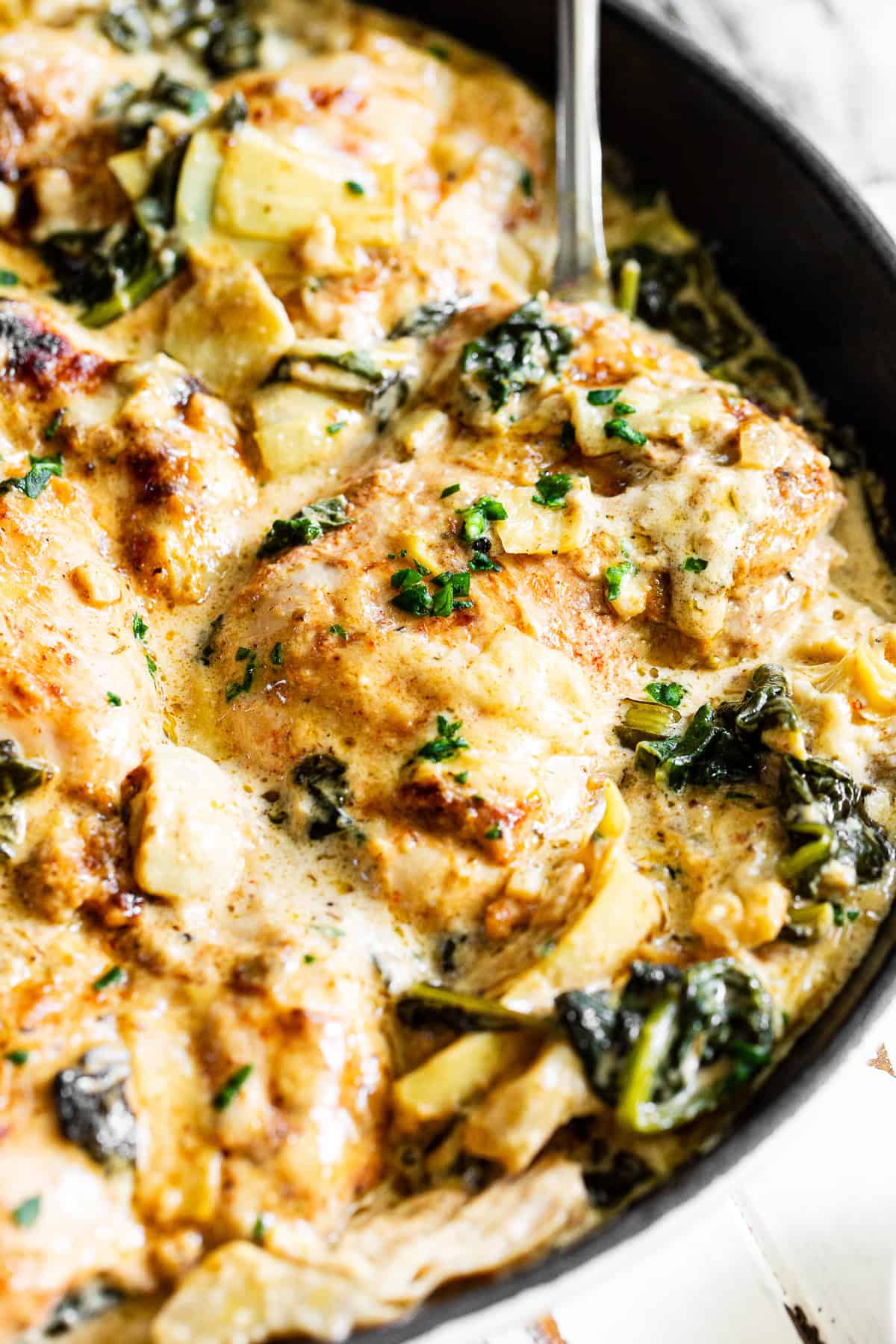 Creamy spinach artichoke chicken in a skillet with chicken thighs, spinach, artichoke hearts and rich dairy-free cream sauce.