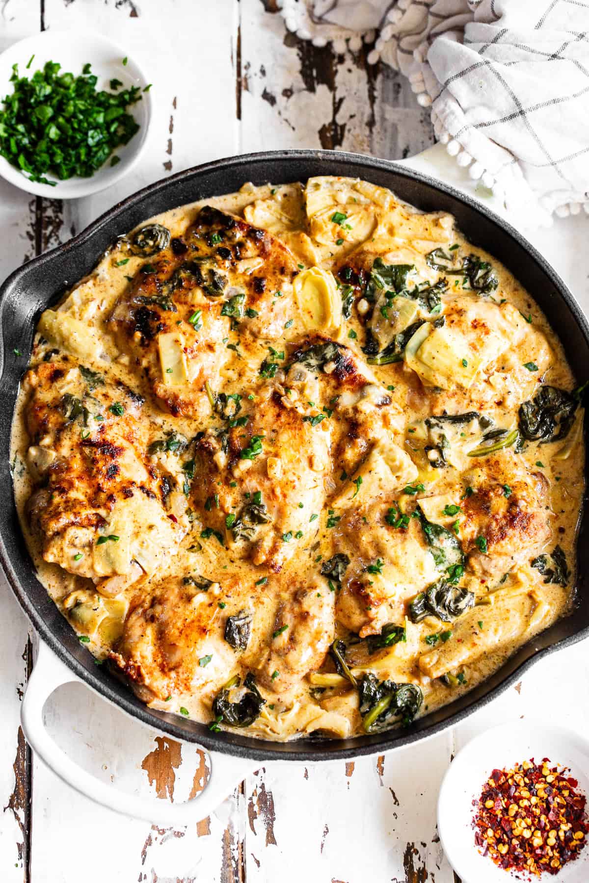 Creamy spinach artichoke chicken recipe made in one skillet with chicken thighs, spinach and artichoke hearts.