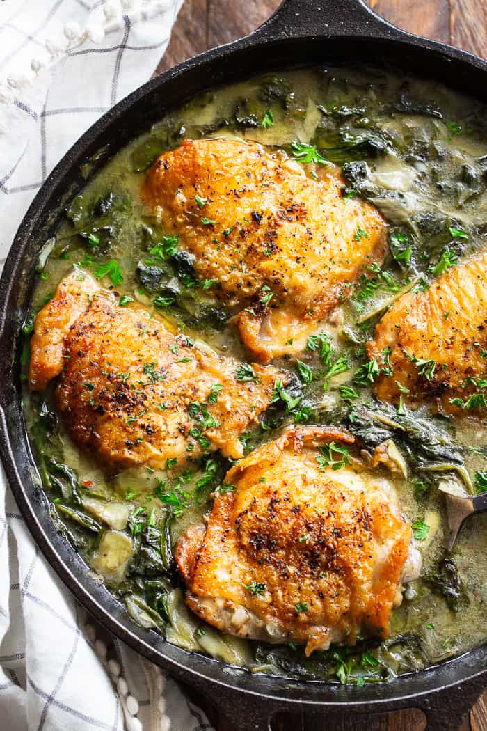 spinach artichoke chicken thighs in a cast iron skillet