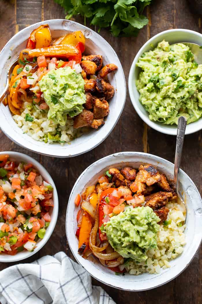 These Paleo Chicken Burrito Bowl are packed with tons of flavor and goodies!  Bite size seasoned chicken thighs, zesty cauliflower rice, pepper and onions plus and easy guac make these bowls healthy, filling, and a family favorite.  Whole30 and keto friendly.