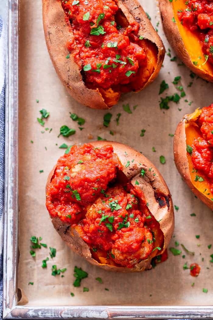 These Italian Meatball Stuffed Sweet Potatoes are flavor packed and easy to make!  Quick and easy pan fried Italian meatballs are simmered in sauce and served over perfectly baked sweet potatoes for a paleo and Whole30 meal that’s filing and addicting! 