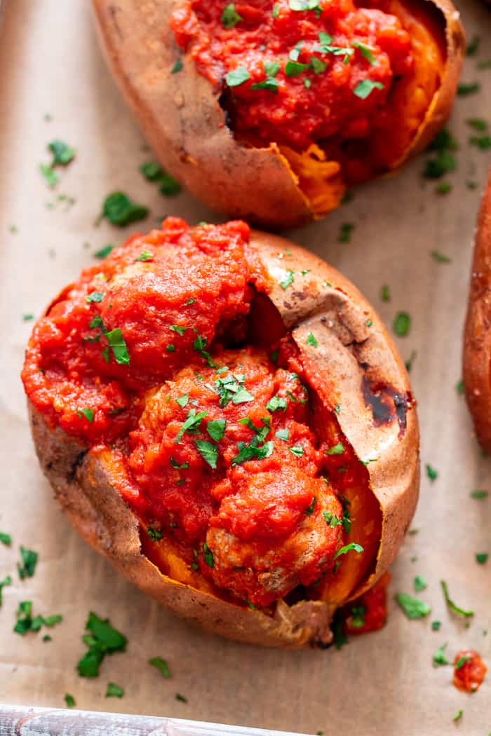 These Italian Meatball Stuffed Sweet Potatoes are flavor packed and easy to make!  Quick and easy pan fried Italian meatballs are simmered in sauce and served over perfectly baked sweet potatoes for a paleo and Whole30 meal that’s filing and addicting! 