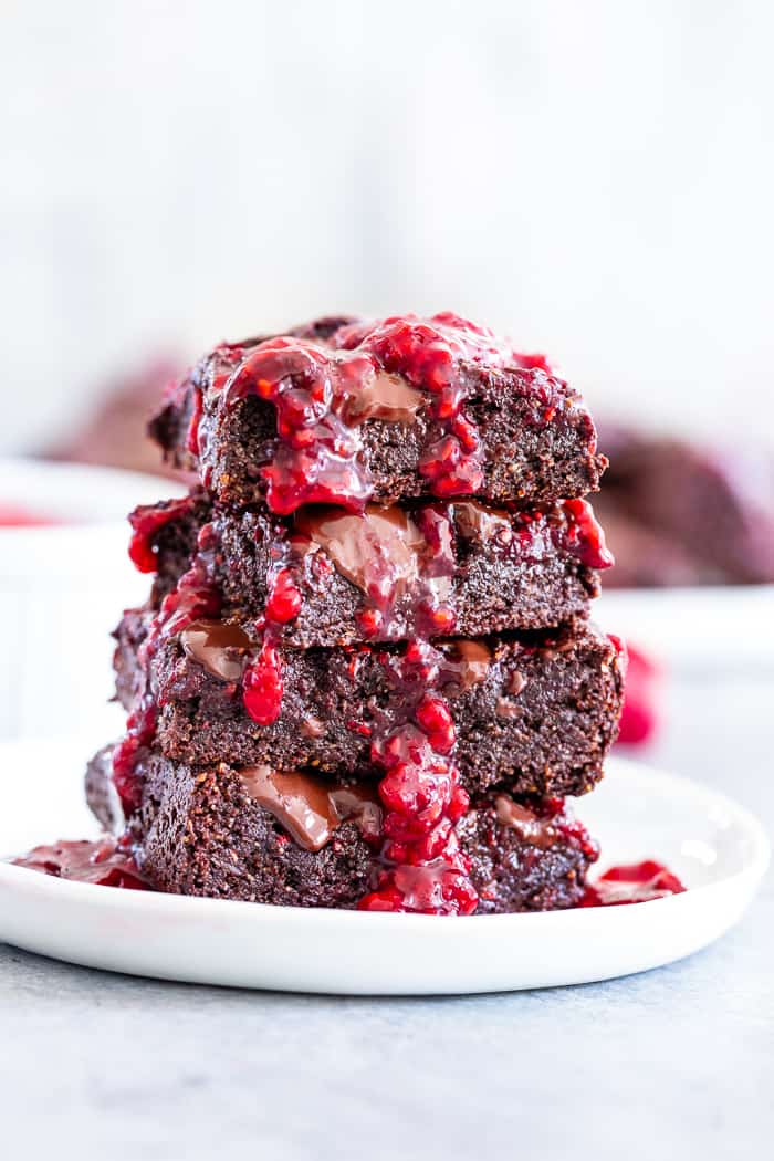 These insanely fudgy raspberry brownies are easy to whip up and just happen to be good for you!  Rich chocolate paleo and vegan brownie batter is baked with an easy raspberry sauce for the ultimate fruit and chocolate combo.  They’re gluten-free, dairy-free, and completely addicting!