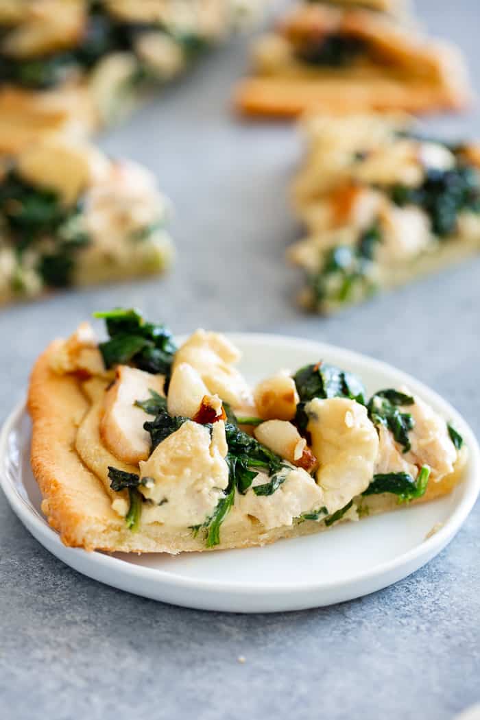 This white pizza has a super tasty roasted garlic cashew cheese sauce with sautéed spinach and chicken, plus more roasted garlic.  Everything is baked on the best easy paleo pizza crust for a fun, filling and delicious paleo and dairy free pizza.