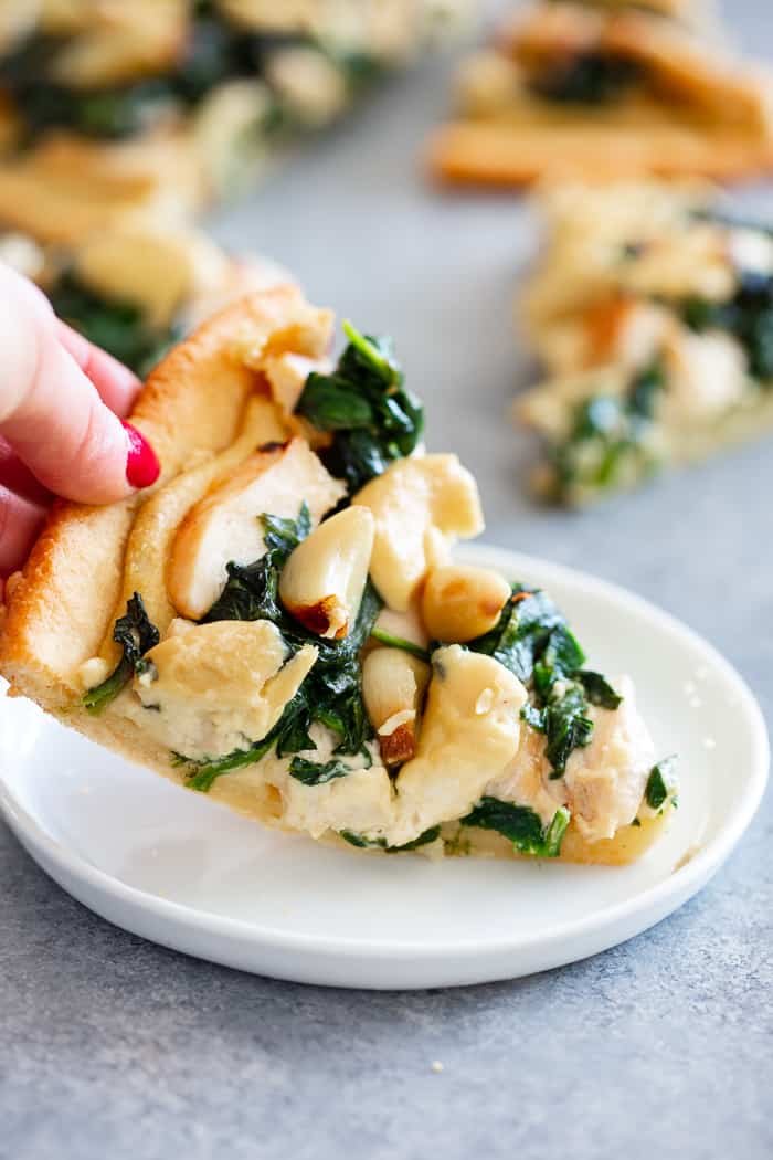 This white pizza has a super tasty roasted garlic cashew cheese sauce with sautéed spinach and chicken, plus more roasted garlic.  Everything is baked on the best easy paleo pizza crust for a fun, filling and delicious paleo and dairy free pizza.