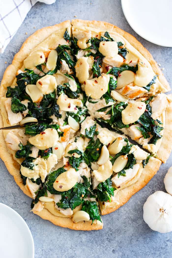 This white pizza has a super tasty roasted garlic cashew cheese sauce with sautéed spinach and chicken, plus more roasted garlic.  Everything is baked on the best easy paleo pizza crust for a fun, filling and delicious paleo and dairy free pizza.