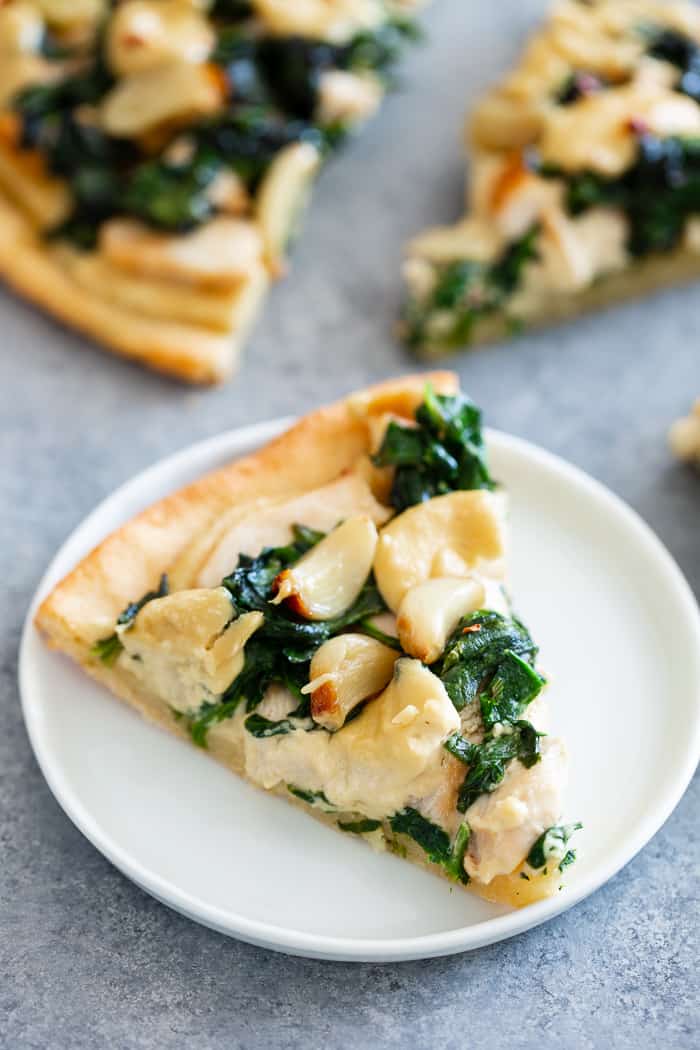 This white pizza has a super tasty roasted garlic cashew cheese sauce with sautéed spinach and chicken, plus more roasted garlic.  Everything is baked on the best easy paleo pizza crust for a fun, filling and delicious paleo and dairy free pizza.