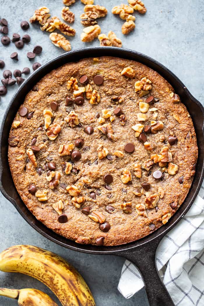 This banana gooey chocolate chip skillet cookie is a dessert that’s heathy enough for breakfast!  It’s loaded with healthy fats, sweetened with bananas and unrefined maple sugar and packed with dark chocolate chips and walnuts.  Gluten-free, grain free, paleo, dairy free, and vegan too!