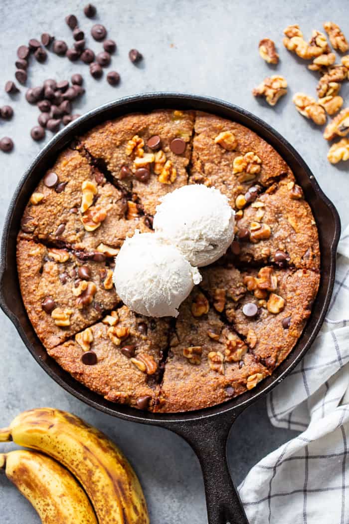 This banana gooey chocolate chip skillet cookie is a dessert that’s heathy enough for breakfast!  It’s loaded with healthy fats, sweetened with bananas and unrefined maple sugar and packed with dark chocolate chips and walnuts.  Gluten-free, grain free, paleo, dairy free, and vegan too!