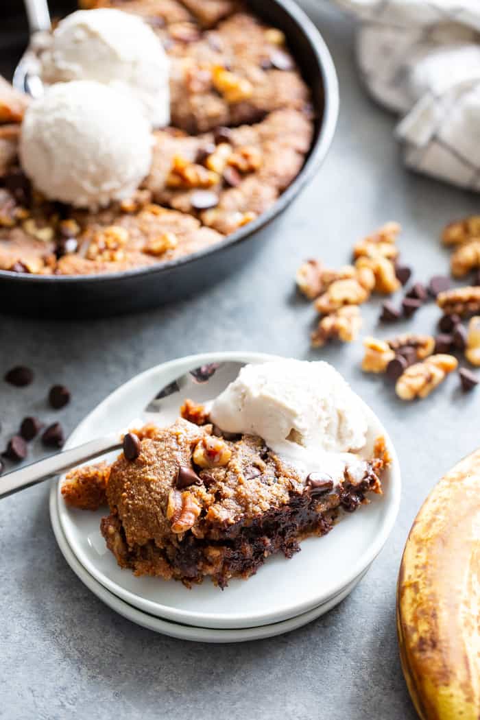 This banana gooey chocolate chip skillet cookie is a dessert that’s heathy enough for breakfast!  It’s loaded with healthy fats, sweetened with bananas and unrefined maple sugar and packed with dark chocolate chips and walnuts.  Gluten-free, grain free, paleo, dairy free, and vegan too!