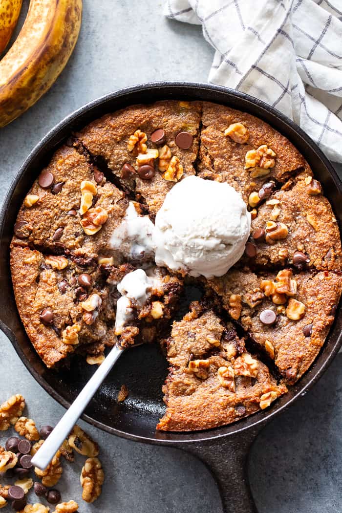 This banana gooey chocolate chip skillet cookie is a dessert that’s heathy enough for breakfast!  It’s loaded with healthy fats, sweetened with bananas and unrefined maple sugar and packed with dark chocolate chips and walnuts.  Gluten-free, grain free, paleo, dairy free, and vegan too!