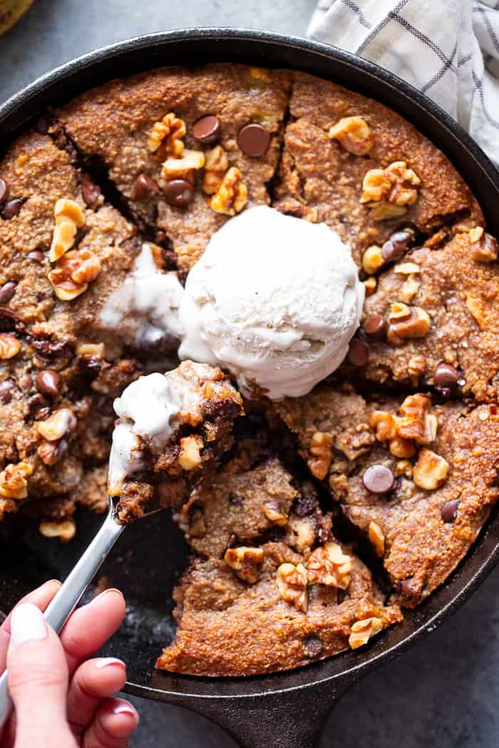 This banana gooey chocolate chip skillet cookie is a dessert that’s heathy enough for breakfast!  It’s loaded with healthy fats, sweetened with bananas and unrefined maple sugar and packed with dark chocolate chips and walnuts.  Gluten-free, grain free, paleo, dairy free, and vegan too!