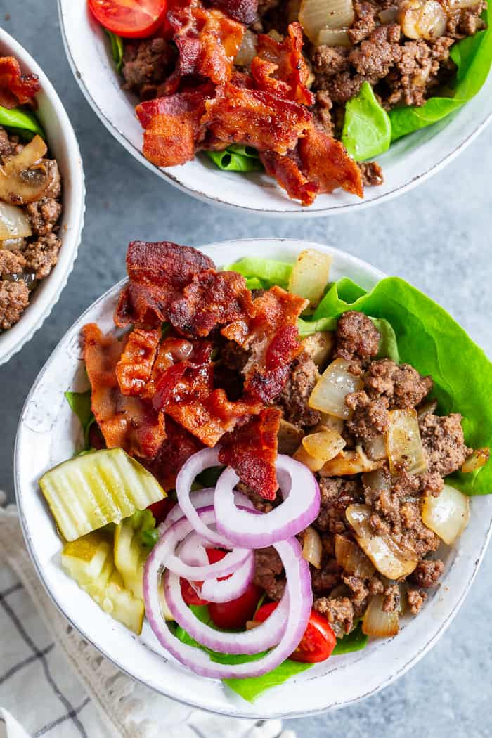These deconstructed loaded bacon burger bowls have all the goodies you love in a burger!  Sautéed mushrooms and onions, crispy bacon, pickles, tomatoes, red onion and a “cheesy” ranch sauce!  Paleo, Whole30, and keto friendly and seriously delicious!