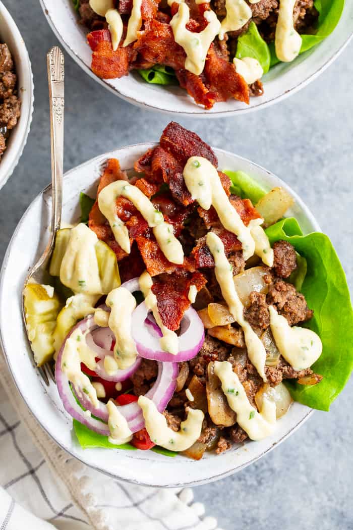 These deconstructed loaded bacon burger bowls have all the goodies you love in a burger!  Sautéed mushrooms and onions, crispy bacon, pickles, tomatoes, red onion and a “cheesy” ranch sauce!  Paleo, Whole30, and keto friendly and seriously delicious!