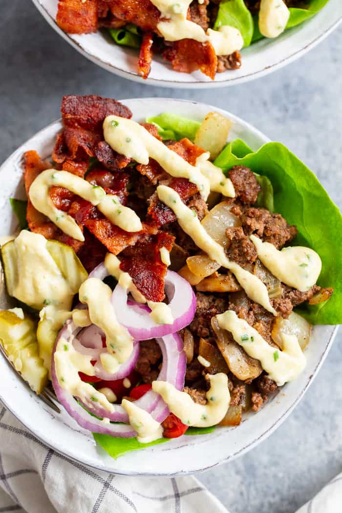 These deconstructed loaded bacon burger bowls have all the goodies you love in a burger!  Sautéed mushrooms and onions, crispy bacon, pickles, tomatoes, red onion and a “cheesy” ranch sauce!  Paleo, Whole30, and keto friendly and seriously delicious!